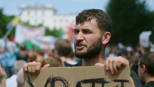 Ansikte porträtt av människan på oppositionen politisk rally med plakat banner ropar. — Stockvideo