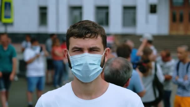 Sokaklarda grev yapan kalabalığın arasında covid-19 maskeli çevik kuvvet eylemcisinin portresi — Stok video