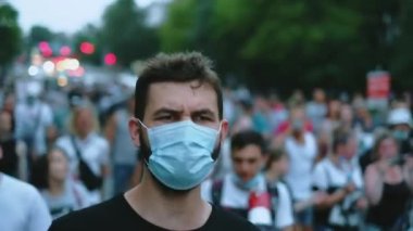 Coronavirus salgını şehir kalabalığında maskeli eylemci yürüyüşleri.