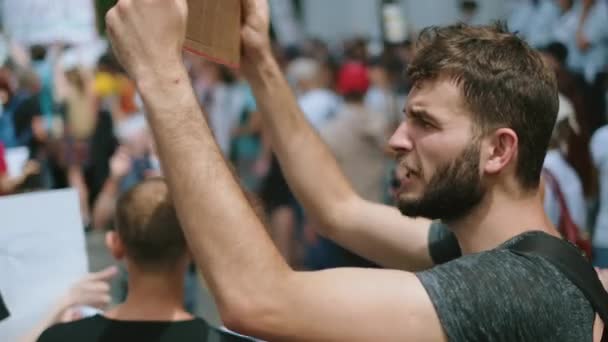 Bearded angry guy with poster sign shouts in crowd of political strike activists — Stock Video