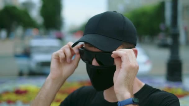 Agencia del FBI provocador masculino en coronavirus mascarilla negra, gafas y gorra. — Vídeo de stock