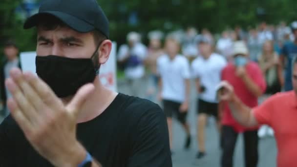 Rebel regulations activist in face mask claps hands in crowded marching people. — Stock Video