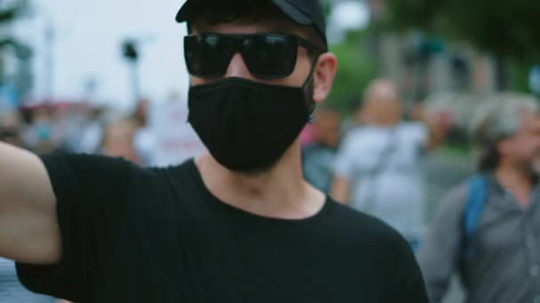 Pandemic rules opposition activist. Rebel in eyeglasses and mask waves fist arm. — Stock Video