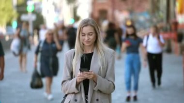 Açık renk saçlı iş kadınının portresi cep telefonuna mesaj yazıyor..