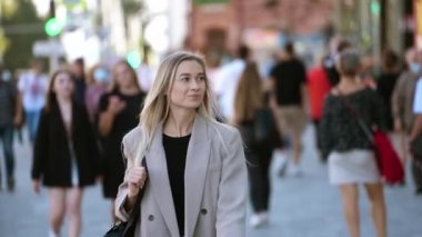 Güzel sarışın kız şehrin arka sokaklarında yürüyor. Çekici gülümseyen bayan..