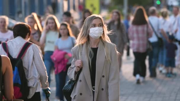 Kvinnan i Coronavirus facemask går på stadens gator. Städernas pandemi, Covid 19. — Stockvideo