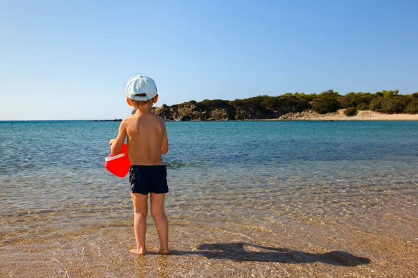 Boy with red bucket on beach — Stock Photo, Image