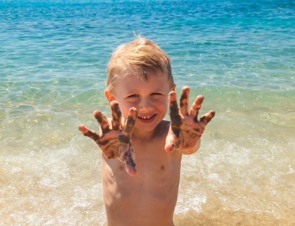 Little boy shows palms in sand — Stock Photo, Image