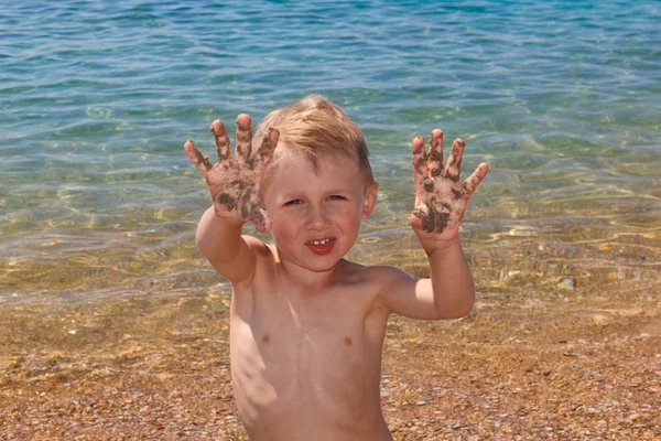 Little boy shows palms in sand — Stock Photo, Image