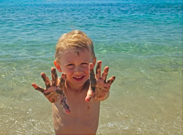 Little boy shows palms in sand — Stock Photo, Image