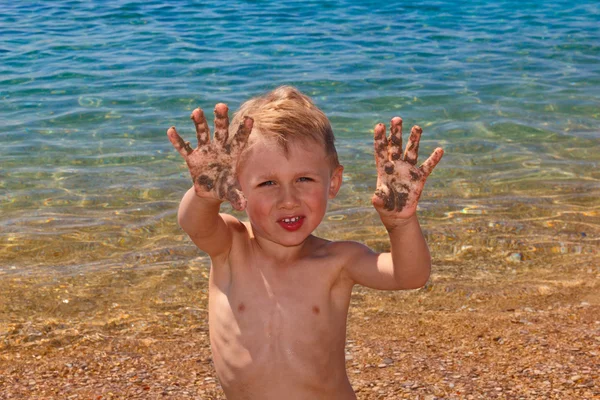 Little boy shows palms in sand — Stock Photo, Image