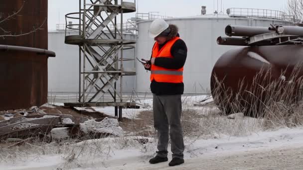 Ingeniero usando tableta PC cerca de los tanques de aceite — Vídeo de stock