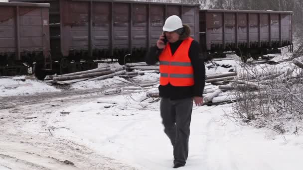 Залізничний офіцер, що йде біля вантажних вагонів — стокове відео