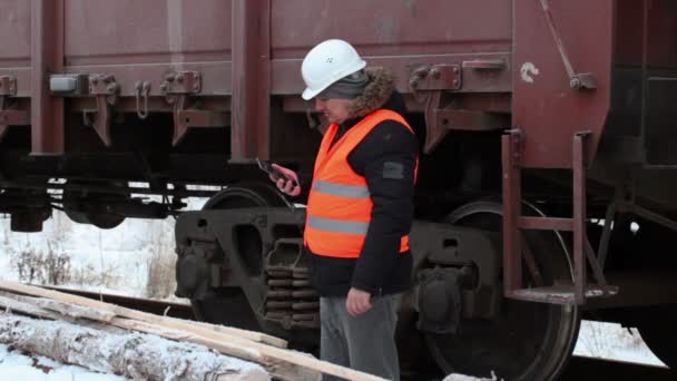 Oficial de ferrocarril tomar fotos cerca de vagones de carga — Vídeos de Stock