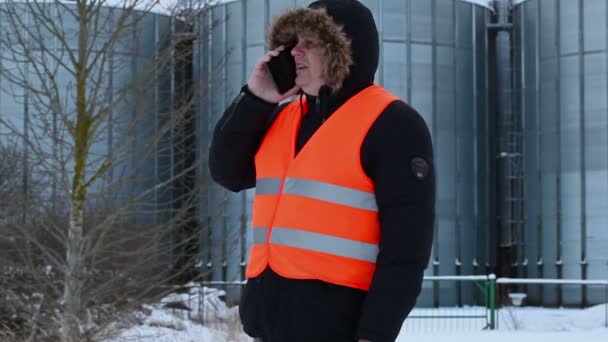 Engenheiro falando no telefone inteligente perto de tanques no inverno — Vídeo de Stock