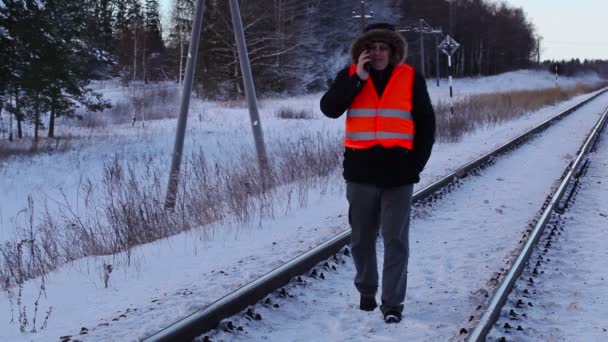 Railway employee using smartphone on railway in winter — Stock Video