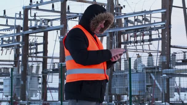 Electricista con tablet PC en planta de energía en invierno — Vídeos de Stock