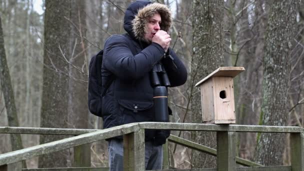 Ornithologist with binoculars on the bridge near bird cage — Stock Video