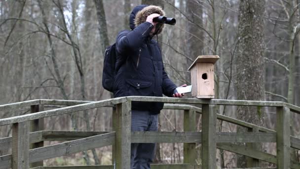 Ornitolog z lornetki i tablet Pc w pobliżu klatka dla ptaków — Wideo stockowe
