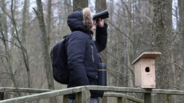 Ornitólogo con prismáticos y jaula de aves en el parque en el puente — Vídeos de Stock