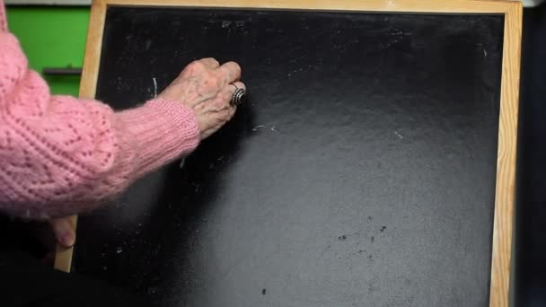 Old woman writing word HEALTH on blackboard — Stock Video