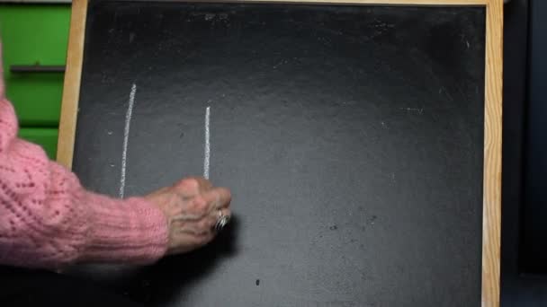 Old woman writing word LIFE on blackboard — Stock Video