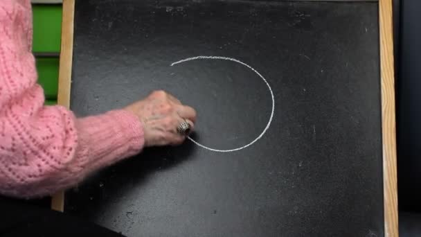 Old woman drawing unhappy smiley on blackboard — Stock Video