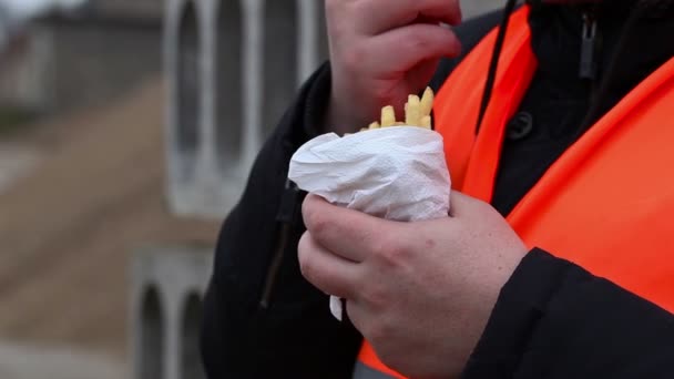 Рабочий ест картошку фри — стоковое видео
