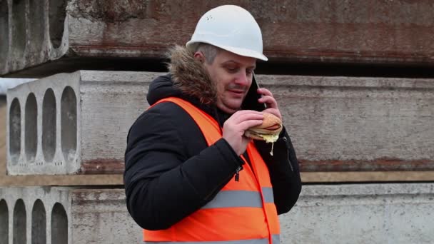 Работник со смартфоном и гамбургером на открытом воздухе — стоковое видео