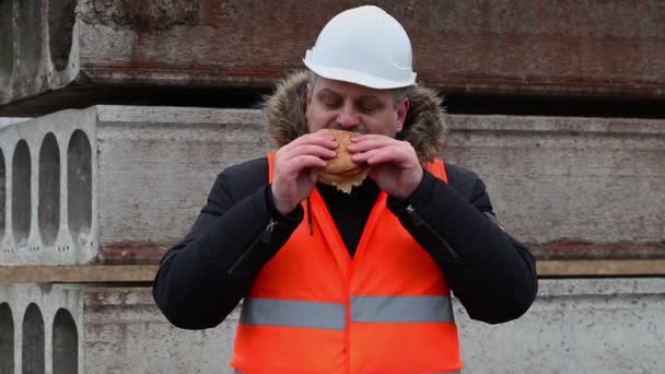 Arbeiter isst Hamburger auf Baustelle — Stockvideo