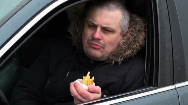Человек ест картошку фри в машине — стоковое видео