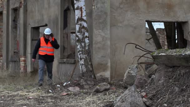 Superviseur de bâtiment parlant sur smartphone près des bâtiments abandonnés — Video