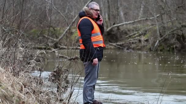 Milieu inspecteur met smartphone in de buurt van de rivier — Stockvideo