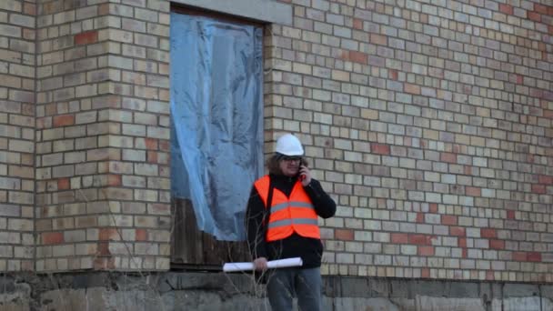 Inspector de edificio hablando por teléfono inteligente cerca del edificio — Vídeos de Stock