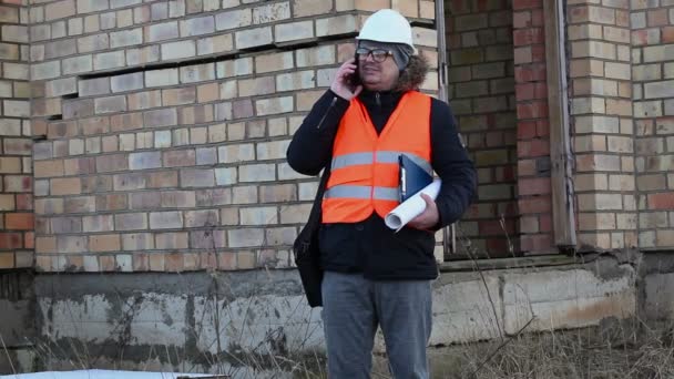 Строительный инспектор с документами, проверяющими здание — стоковое видео