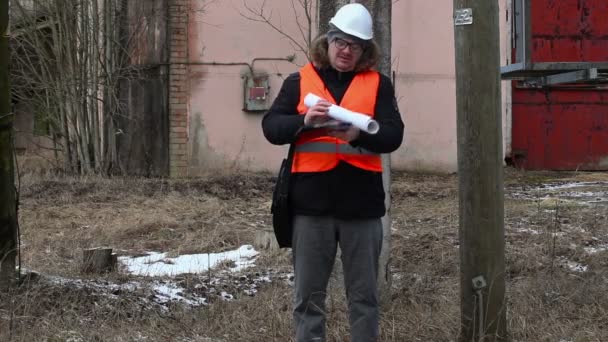 Ingenieur met documentatie in de buurt van powerline — Stockvideo