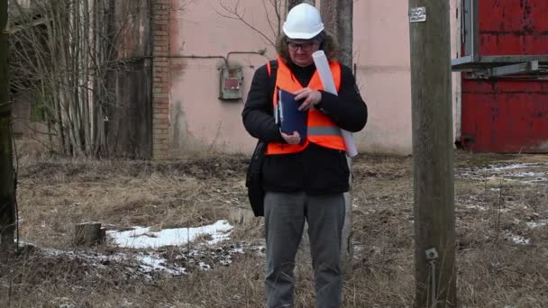 Ingenieur überprüft Dokumentation in der Nähe der Stromleitung — Stockvideo