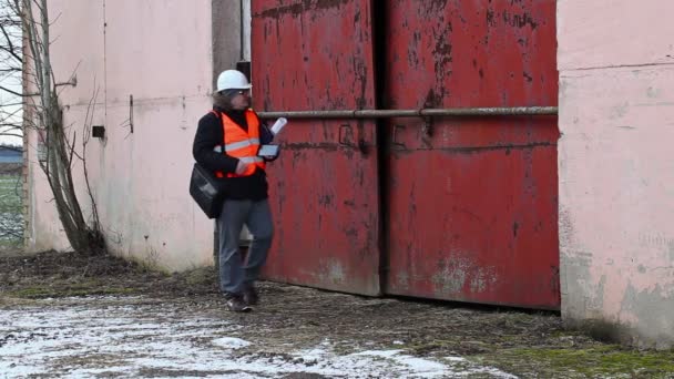 Инженер с планшетным ПК и документация возле здания — стоковое видео