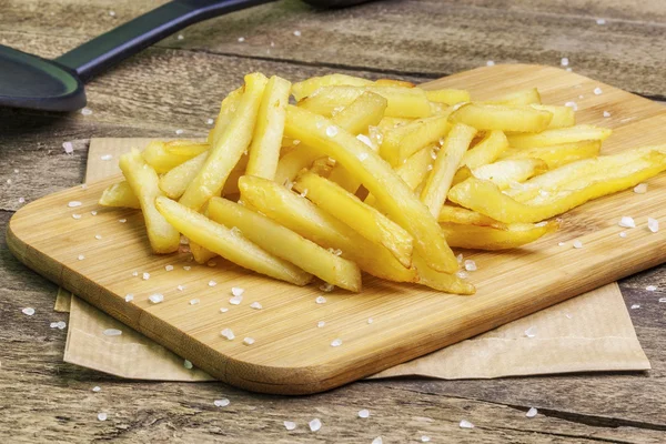 Papas fritas con sal sobre madera — Foto de Stock