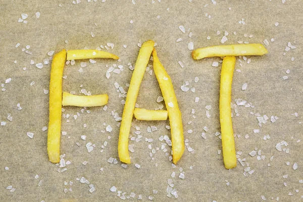 Batatas fritas inscrição FAT com sal ao redor — Fotografia de Stock