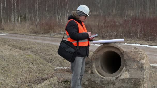 Engineer using tablet PC at the concrete pipes — Stock Video