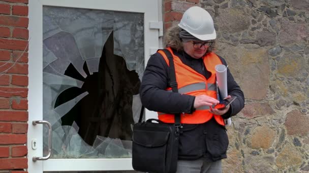 Inspektor budowlany z tabliczka Pc w pobliżu rozbite okno — Wideo stockowe