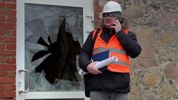 Inspector de edificio con teléfono inteligente cerca de la ventana rota — Vídeo de stock