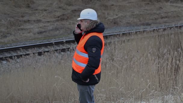 Εργάτης Railroad με έξυπνο τηλέφωνο κοντά σιδηρόδρομος — Αρχείο Βίντεο