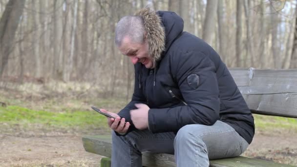 Glücklicher Mann lacht im Park auf einer Bank — Stockvideo