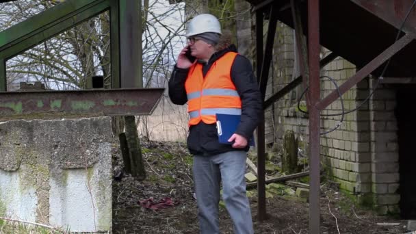 Ingeniero con teléfono celular en la antigua fábrica — Vídeos de Stock