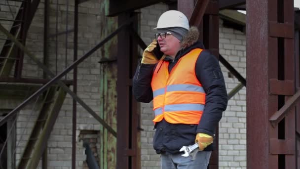 Arbeiter mit verstellbarem Schraubenschlüssel telefoniert — Stockvideo