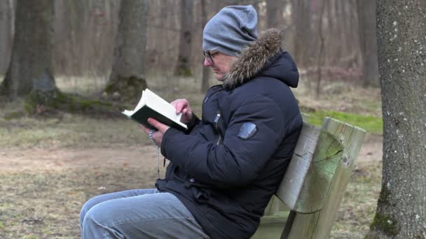 Człowiek, czytanie Biblii i modląc się na ławce w parku — Wideo stockowe