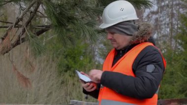 Orman işçisi ormanda ağaç yakınındaki resim çekmek 