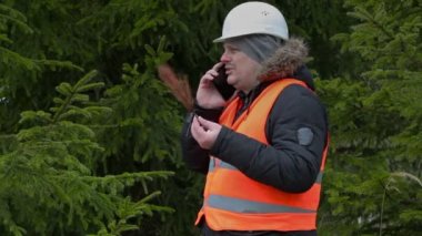 Orman işçisi solmuş Şubeler ve ormandaki smartphone ile 